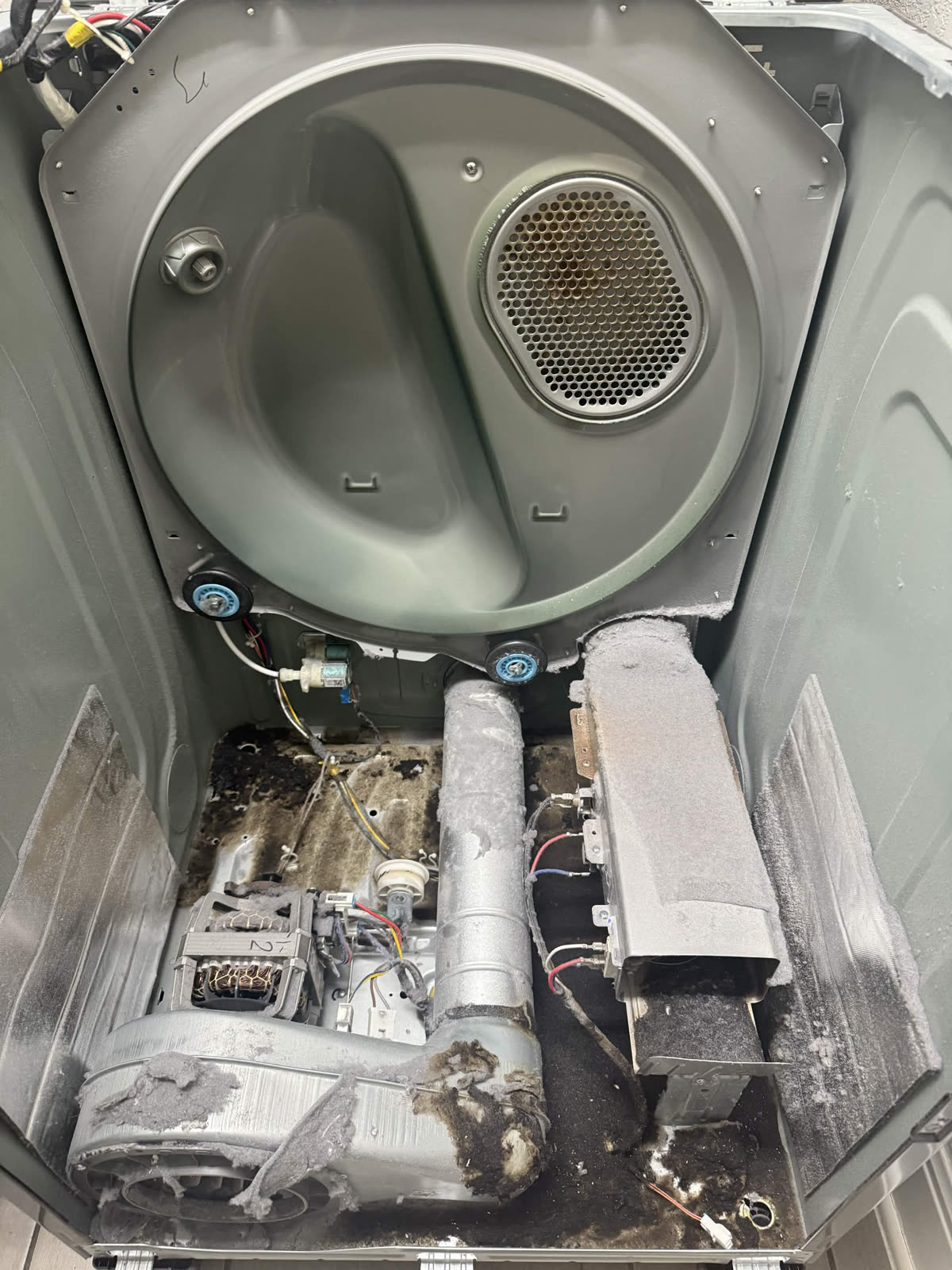 Before dryer repair with heavy lint buildup inside the cabinet